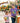 A woman and a young girl are standing together in an amusement park, both wearing matching t-shirts with cartoon characters.